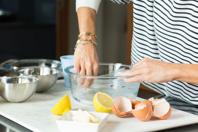 Woman greasing the baking dish while cooking apple pie in the modern kitchen