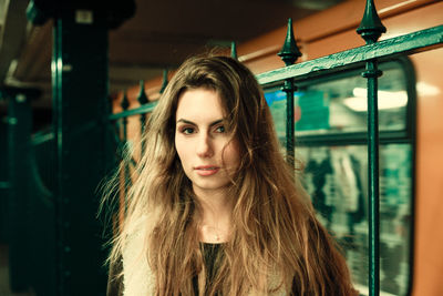 Portrait of young woman with long hair standing at railroad station
