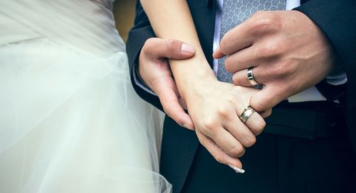Close-up of married couple holding hands