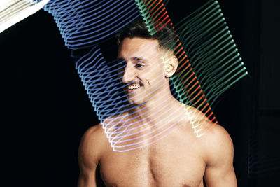 Portrait of shirtless young man against black background