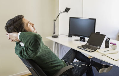 Businessman with hands behind head relaxing at desk in office