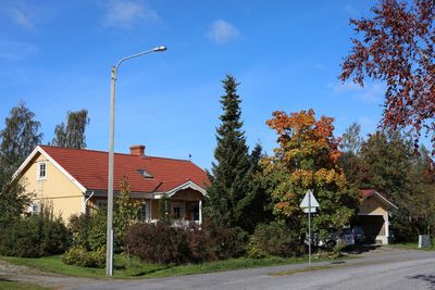 Street amidst houses and trees against blue sky