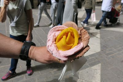 Midsection of people holding ice cream on footpath