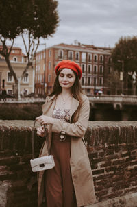 Portrait of beautiful young woman standing against brick wall