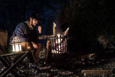 Man sitting by fire pit at night