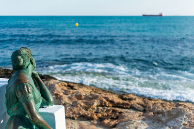 Statue at rock sea shore