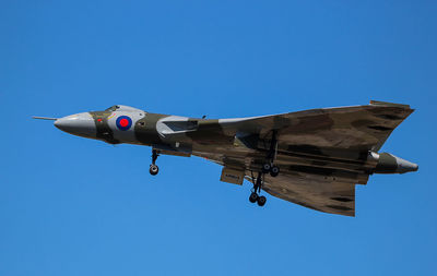 Low angle view of airplane flying against clear blue sky