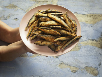 High angle view of hand holding bread in plate on table