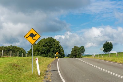 Information sign by empty road against sky