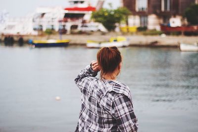 Rear view of woman standing by river in city