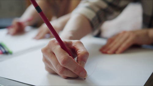 Midsection of teacher teaching drawing to kid