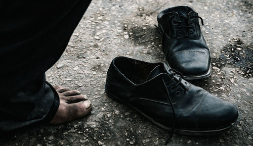 Low section of man standing by shoes on footpath