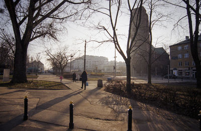 People walking on footpath by buildings in city