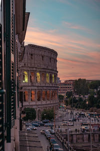 View of historical colosseum building in city during sunset