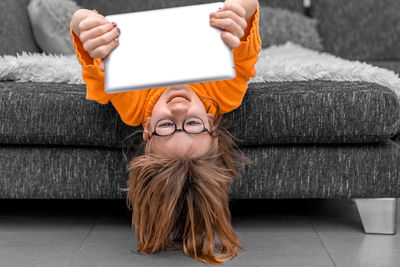 Young woman using digital tablet while sitting on sofa at home