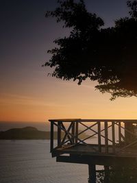 Silhouette tree by sea against sky during sunset