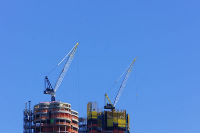 Low angle view of crane against clear blue sky