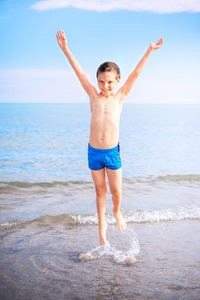 Full length of shirtless boy at beach against sky