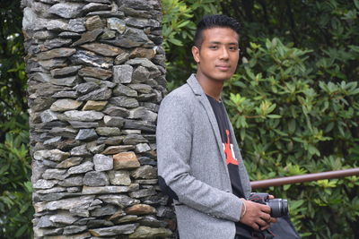 Portrait of young man standing against brick wall