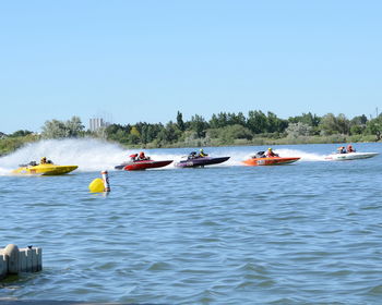 People boating in sea against clear sky 