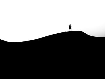 Silhouette person standing on mountain against clear sky