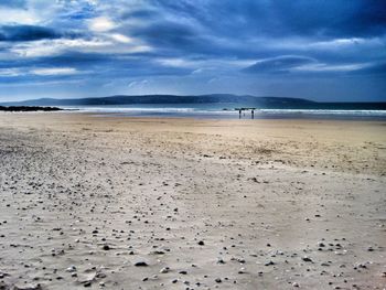 Scenic view of beach against cloudy sky