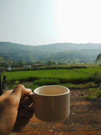 Coffee cup on table by mountains against sky