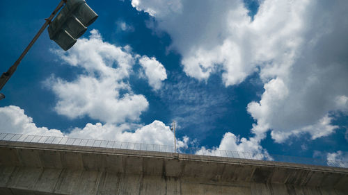 Low angle view of road signal and bridge against sky