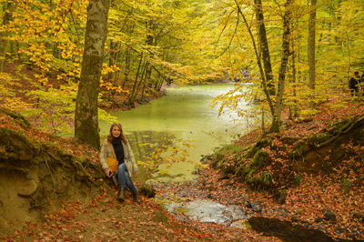 Woman sitting by algae covered lake at yedigoller national park during autumn