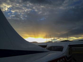 Close-up of airplane on runway against sky during sunset