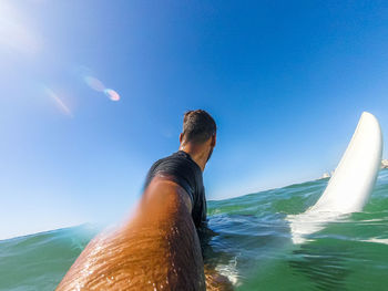 Man in sea against clear blue sky