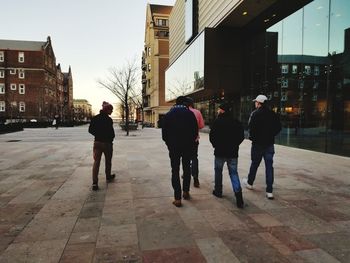 Rear view of people walking on street in city