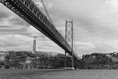 Low angle view of april 25th bridge over tagus river against sky