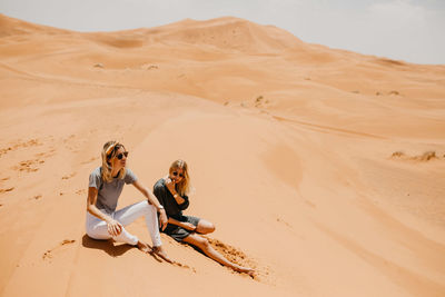 People sitting on sand dune in desert