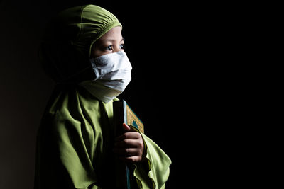 Portrait of a person wearing mask against black background