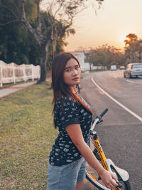 Portrait of smiling young woman standing on road in city