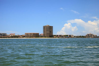 Sea by buildings against blue sky