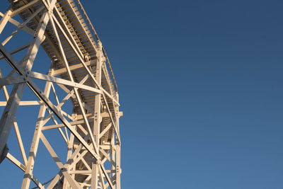 Low angle view of ferris wheel against clear blue sky