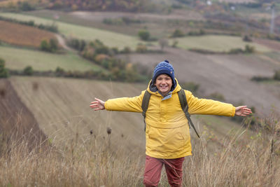 Full length of smiling young woman standing on field