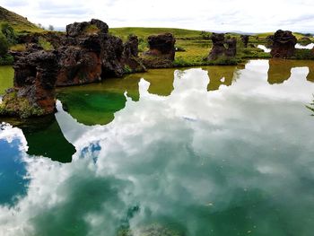 Reflection of rocks in water against sky