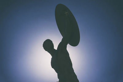 Low angle view of silhouette statue against clear blue sky