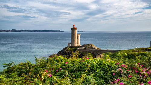 Lighthouse by sea against sky