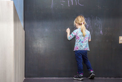 Full length of girl writing on blackboard