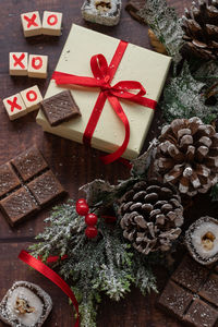 Christmas festive gift box and sweets with seasons decorations on wooden background