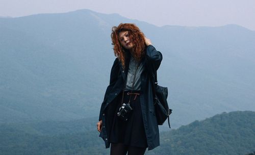 Hiker with camera standing against mountains