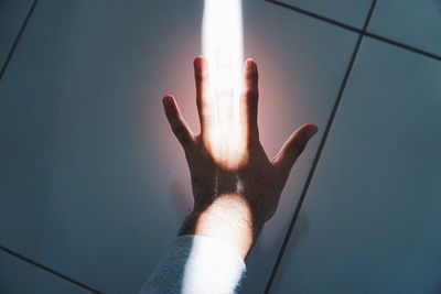 Sunlight falling on hand over tiled floor