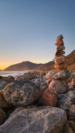 Rear view of man standing on rock at sunset