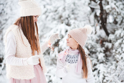Sisters holding sparklers during winter