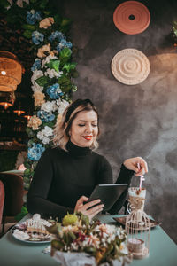 Young woman using phone while sitting on table