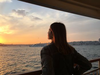 Woman looking at sea against sky during sunset